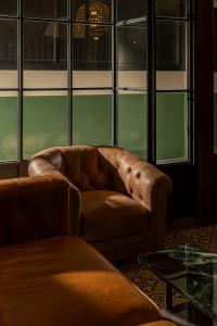 a brown leather couch in a room with windows at Merchant's Gate Songwat in Bangkok