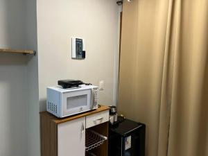 a microwave sitting on top of a table with a curtain at Studio-type apartment in Praia do Forte in Mata de Sao Joao