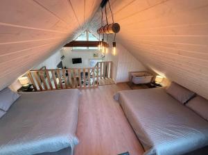 a attic room with two beds and a staircase at Rūdupji Anna in Kalniena
