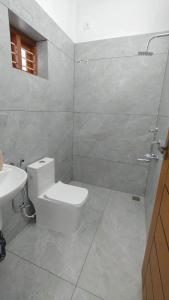 a white bathroom with a toilet and a sink at Luckwin Guest in Anuradhapura