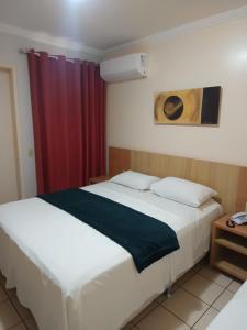 a bedroom with two beds and a red curtain at Flat Di Roma 110A Rio Quente in Rio Quente