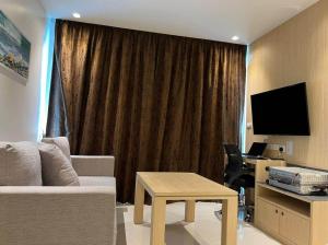 a living room with a couch and a table and a television at Beachfront A405 Seaview Studio Rawai Phuket in Ban Saiyuan (1)