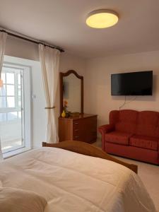 a bedroom with a bed and a red couch at Casa do medio in Corcubión
