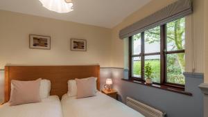 two beds in a room with two windows at Dog Friendly Lakeland Cottage At Windermere Marina Village in Bowness-on-Windermere