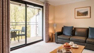 a living room with a couch and a large window at Dog Friendly Lakeland Cottage At Windermere Marina Village in Bowness-on-Windermere