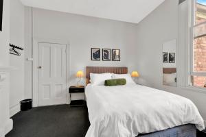 a white bedroom with a large bed and a window at Windsor Green Hotel in Melbourne