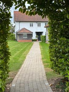 a brick pathway leading to a white house at The Old Rectory in Campsey Ash +5 photos