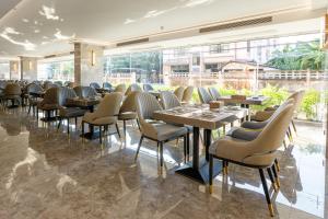 a dining room with tables and chairs and a large window at HK Hotel Bangkok in Ban Bang Toei (1)
