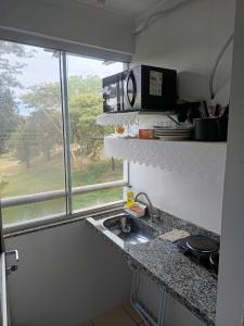 a kitchen counter with a sink and a window at Flat Di Roma 110A Rio Quente in Rio Quente