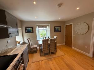 a kitchen with a table and a clock on the wall at Alt-Na-Slat Cottage in Invergarry
