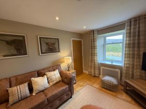 a living room with a couch and a window at Alt-Na-Slat Cottage in Invergarry