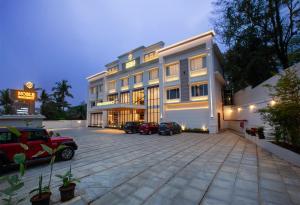 a large building with cars parked in a parking lot at Hotel Noble Residency in Kizhillam