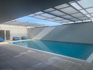 a swimming pool in a building with blue chairs at Sonho de Sesimbra in Sesimbra