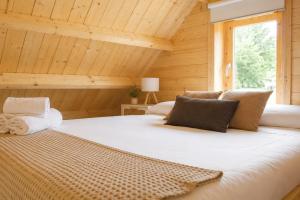 a large white bed in a wooden room with a window at Cabanas Allariz in Allariz