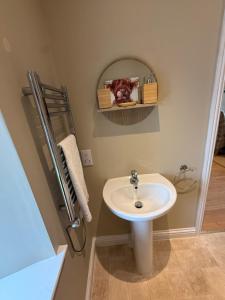 a bathroom with a white sink and a mirror at Alt-Na-Slat Cottage in Invergarry +6 photos