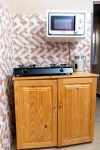 a kitchen with a microwave and a tv on a wall at La casa Cottage in Iringa