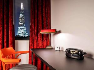 a room with a desk with a view of the shard at ibis Styles London Southwark - near Borough Market in London