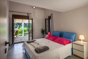 a bedroom with a large bed with red and blue pillows at NeonChic Jacuzzi and Pool Villa in Sani Beach +34 photos