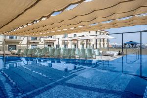 ein Schwimmbecken mit Liegestühlen und einem großen Sonnenschirm in der Unterkunft Hotel Botanica- Limited Edition By Fattal in Haifa