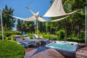 a patio with a hot tub and a hammock at NeonChic Jacuzzi and Pool Villa in Sani Beach