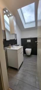 a bathroom with a sink and a toilet and a skylight at Ferienwohnung in Lohrheim in Lohrheim +7 photos
