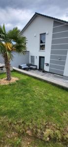 a white house with a palm tree in front of it at Ferienwohnung in Lohrheim in Lohrheim