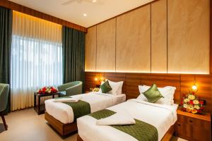 a hotel room with two beds and a window at Hotel Noble Residency in Kizhillam