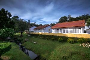 un edificio blanco con techo rojo junto a un río en Holiday Home Resort, en Kodaikanal