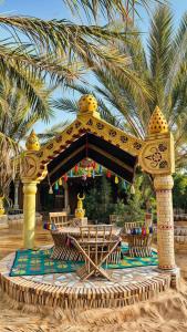 a gazebo on a beach with chairs and a palm tree at Tente et Restaurant ElBey in Douz