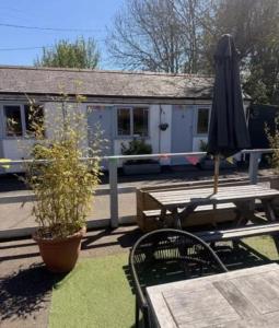 a patio with a table and an umbrella and a building at The Burrow at Black Rabbit Pub in Haybridge