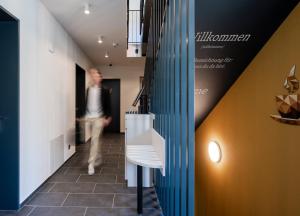 a man walking down a hallway in a building at stay flex Hotel & Apartment in Hertenstein +18 photos