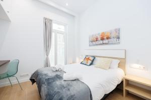a white bedroom with a bed and a desk at YBH Mare Boutique in Vigo