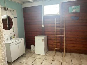a bathroom with a wooden wall with a sink and a refrigerator at Le cocon de Coco in Lamentin +5 photos