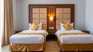 a hotel room with two beds with white and gold pillows at Terrace Alzahra تيراس الزهرا in Jeddah