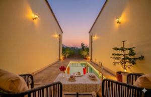 a patio with a table and a swimming pool at Guldaar Sariska - A Luxury Forest Retreat in Tehla