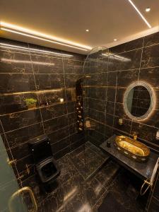 a black tiled bathroom with a sink and a mirror at Anubis Pyramids View Inn in Cairo +30 photos