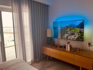 a bedroom with a television on a dresser with a window at Sonho de Sesimbra in Sesimbra