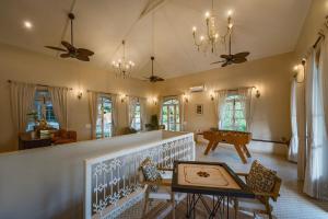 a living room with a table and chairs and ceiling fans at SaffronStays RiverSong Britona in Ribandar