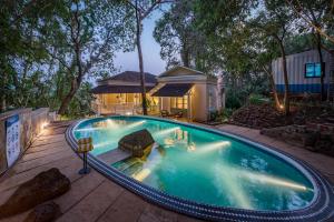 a swimming pool in front of a house at SaffronStays RiverSong Britona in Ribandar