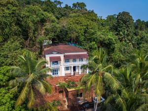 a house on top of a hill with palm trees at SaffronStays RiverSong Britona in Ribandar
