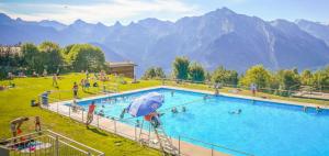 a large swimming pool in a field with people in it at Chalet AS des Pics in Nendaz