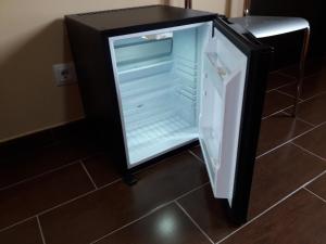 an empty refrigerator with its door open on a floor at Pensión Matarraña in Fayón