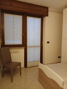 a bedroom with a bed and a chair and windows at Spazioso appartamento su due piani in Leinì