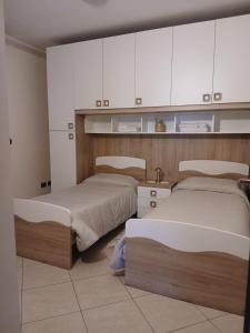 two beds in a room with white cabinets at Spazioso appartamento su due piani in Leinì +19 photos