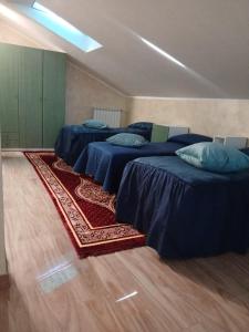 a room with four beds with blue sheets and a rug at Spazioso appartamento su due piani in Leinì