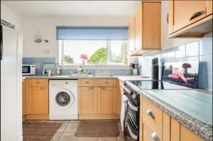 a kitchen with a washing machine and a window at The Waterside Apartment 6 in Largs