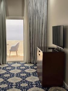 a living room with a television and a table and a chair at Vista Hotel Haql in Al Humaizah