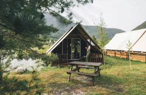 a person standing in front of a small tent at Camping nature 3 étoiles avec piscine - bord de rivière in Chézery-Forens