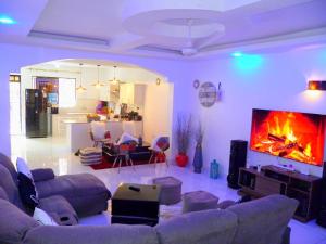 a living room with couches and a large screen tv at Rosa Mystica Diani Bnb in Ukunda Airport