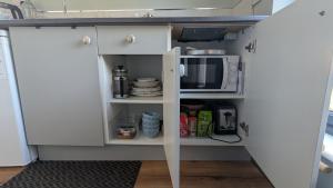 a kitchen with a white cabinet with a microwave at The Boathouse in Ballycotton